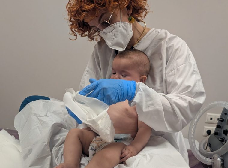 Fisioterapia respiratoria a un bebé en brazos de la profesional